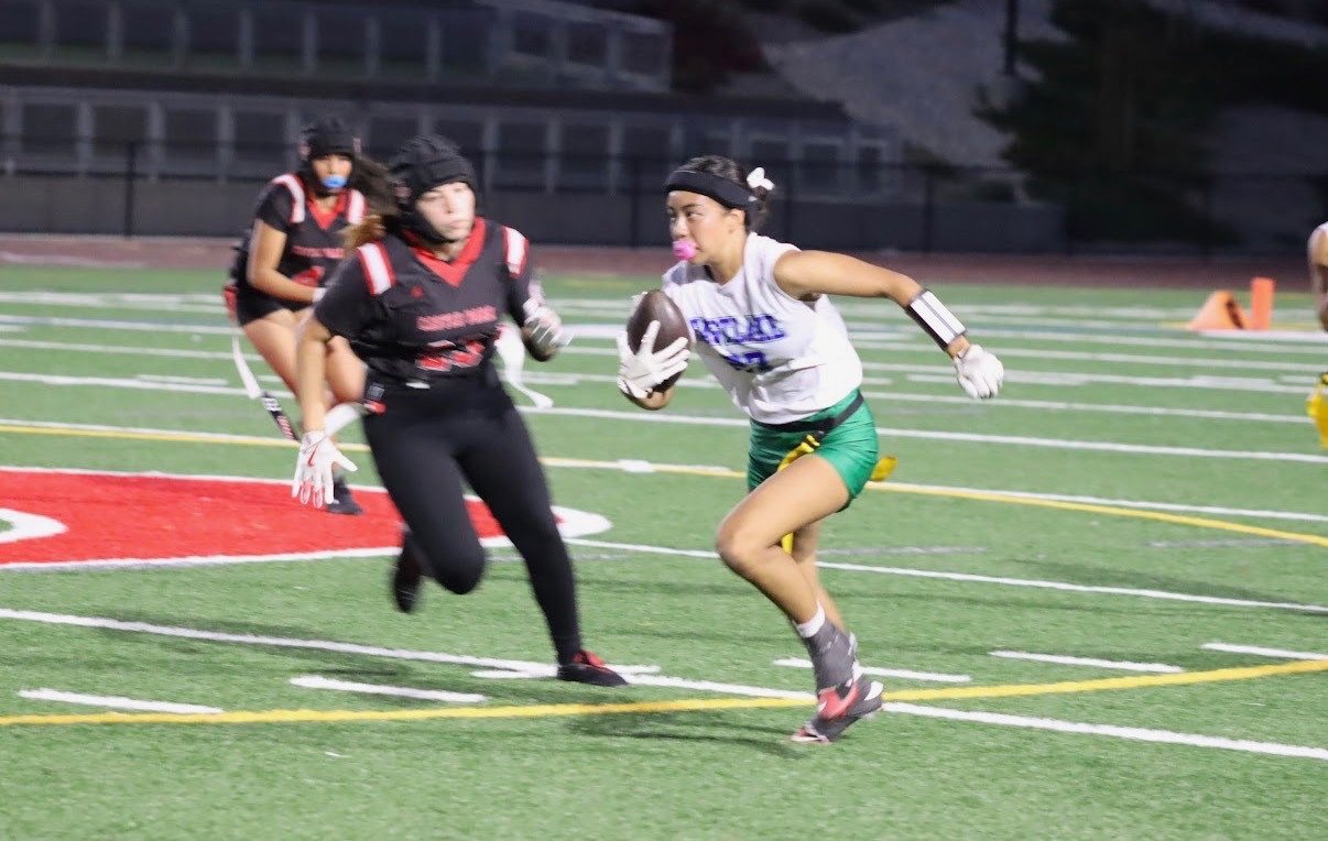 Kaylia Elsas, #27, running with a football tucked against her white jersey