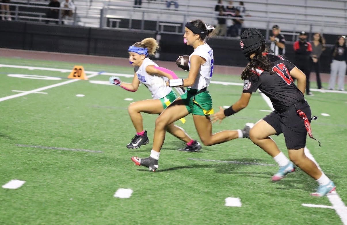 Side view of Kaylia Elsas, #27, running across the field while holding a football